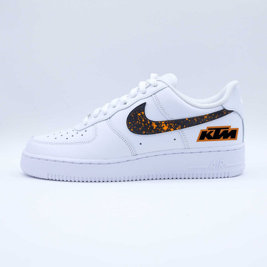 Nike Air Force 1 custom KTM Racing avec swoosh noir éclaboussé d’orange et logo moto sur talon
