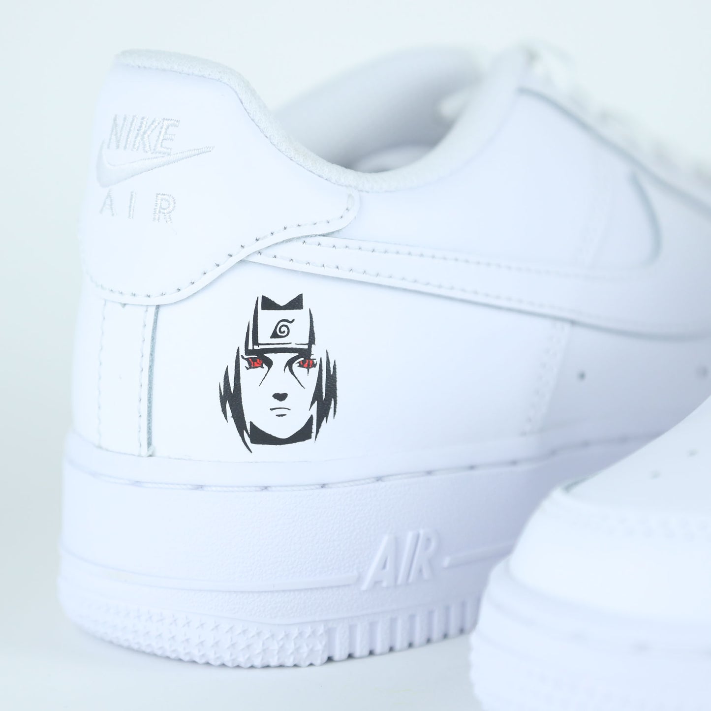 Nike Air Force 1 custom naruto manga Sasuke avec logo de Konoha et visage stylisé de Sasuke Uchiha