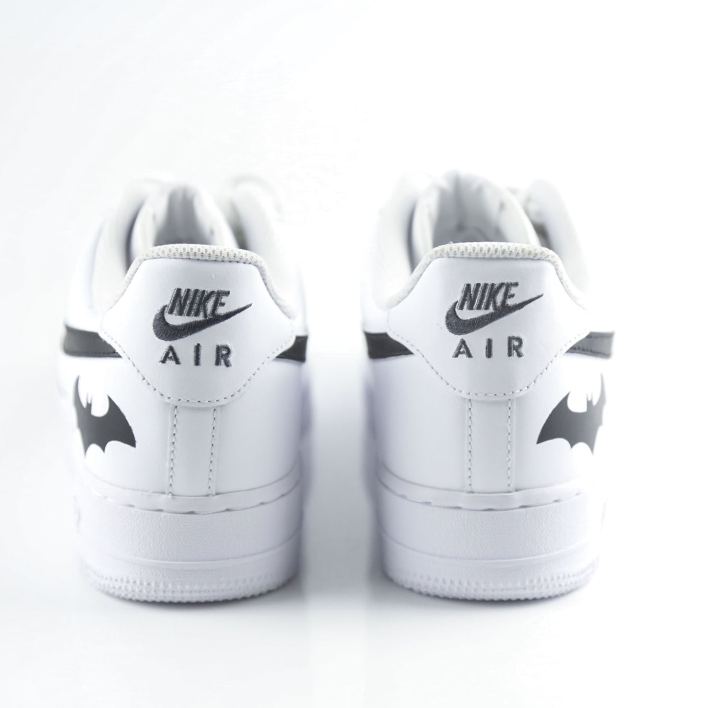 Nike Air Force 1 Custom blanche avec swoosh noir et logo Batman à l’arrière, inspirée de Gotham City, Batman, le Joker et l’univers DC Comics. Sneakers customisées streetwear haut de gamme pour fans de super-héros, comics et baskets personnalisées.