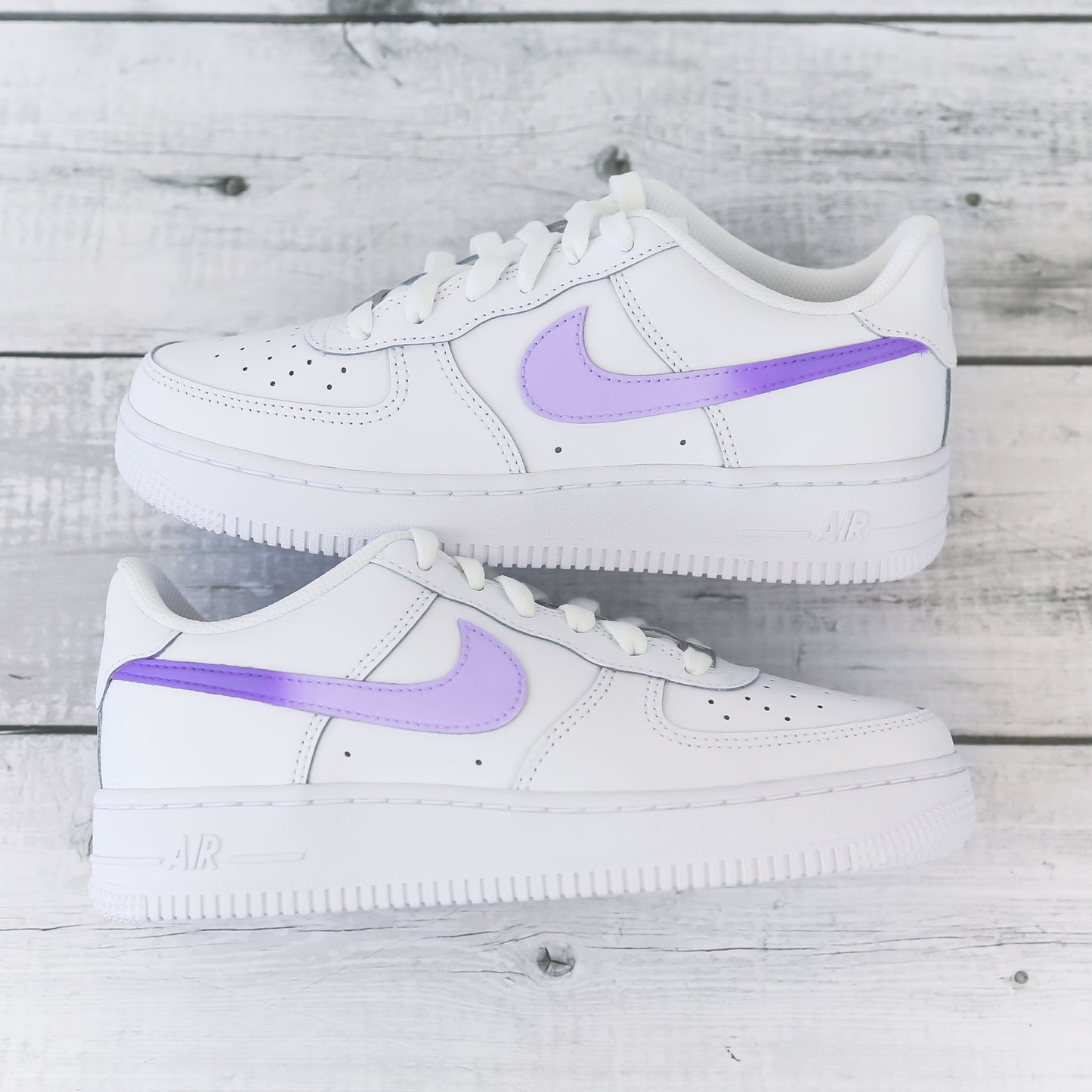 Nike Air Force 1 custom avec swoosh violet pastel sur fond bois clair