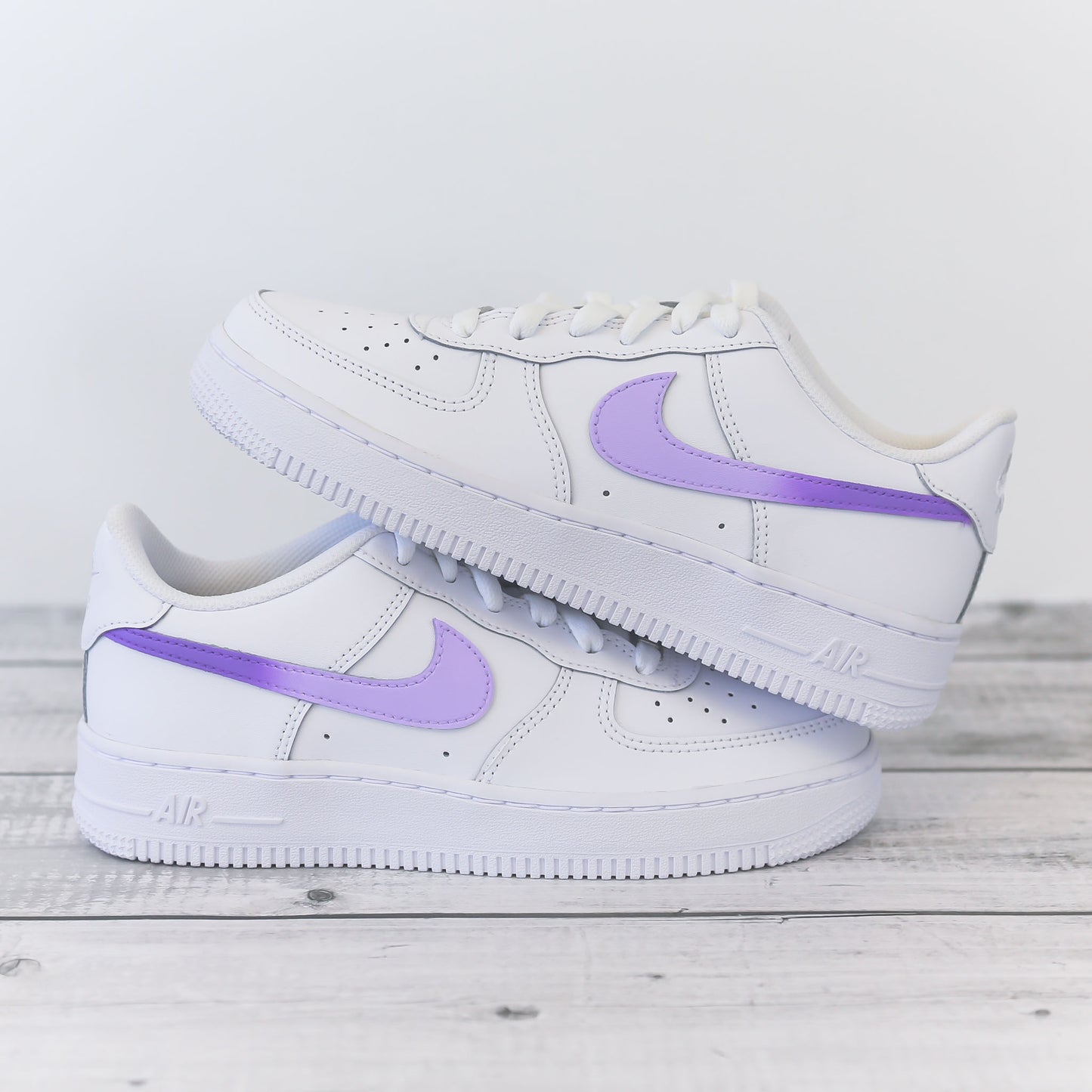Nike Air Force 1 custom avec swoosh violet pastel sur fond bois clair