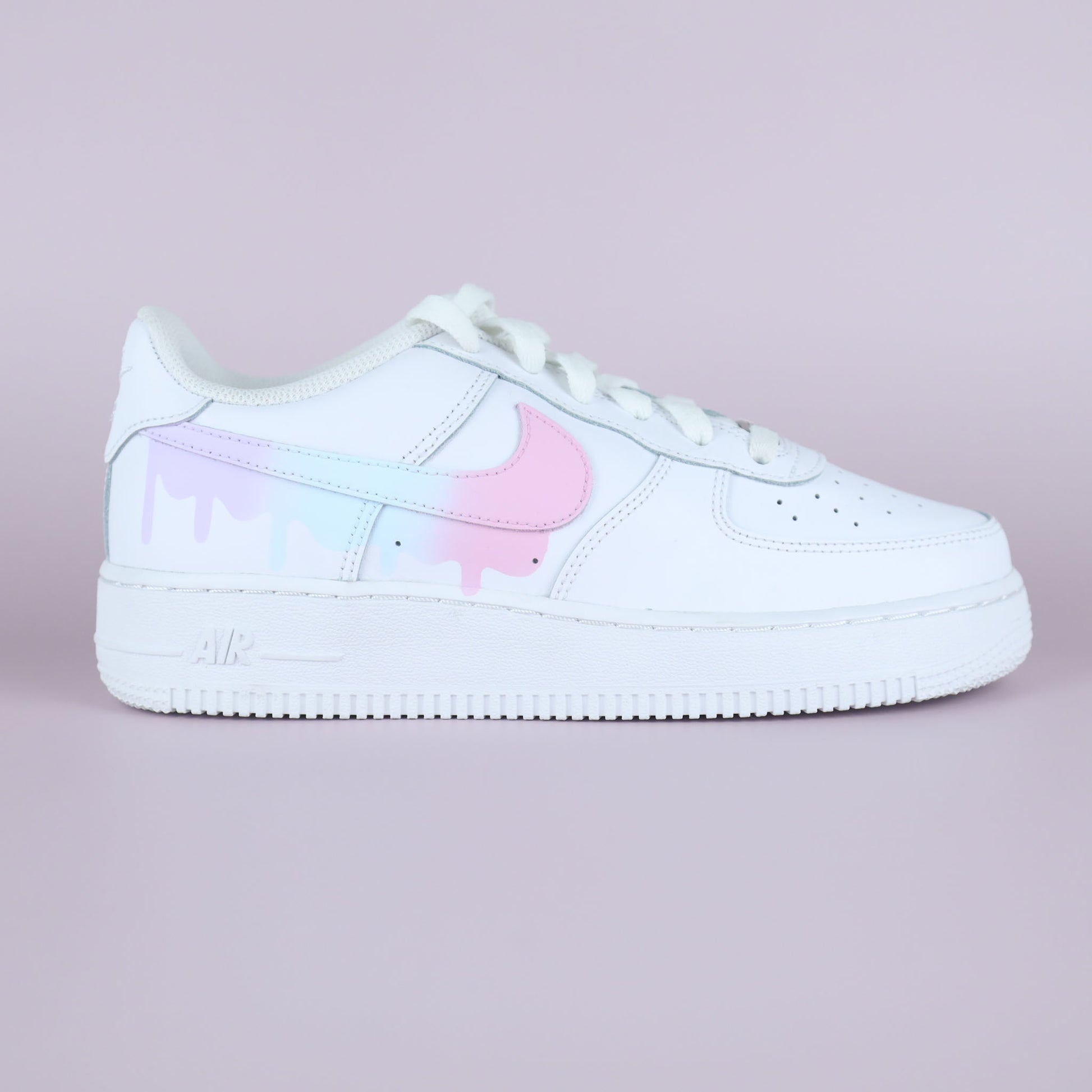 Nike Air Force 1 custom pastel drip avec swoosh rose et effet peinture coulant, vue latérale sur fond rose clair