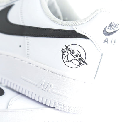  Nike Air Force 1 Custom blanche inspirée de Star Wars et de la série The Mandalorian, avec illustration Baby Yoda (Grogu) et détails rappelant l’armure du Mandalorien. Sneakers customisées streetwear geek pour fans de science-fiction et collectionneurs de l’univers Star Wars.