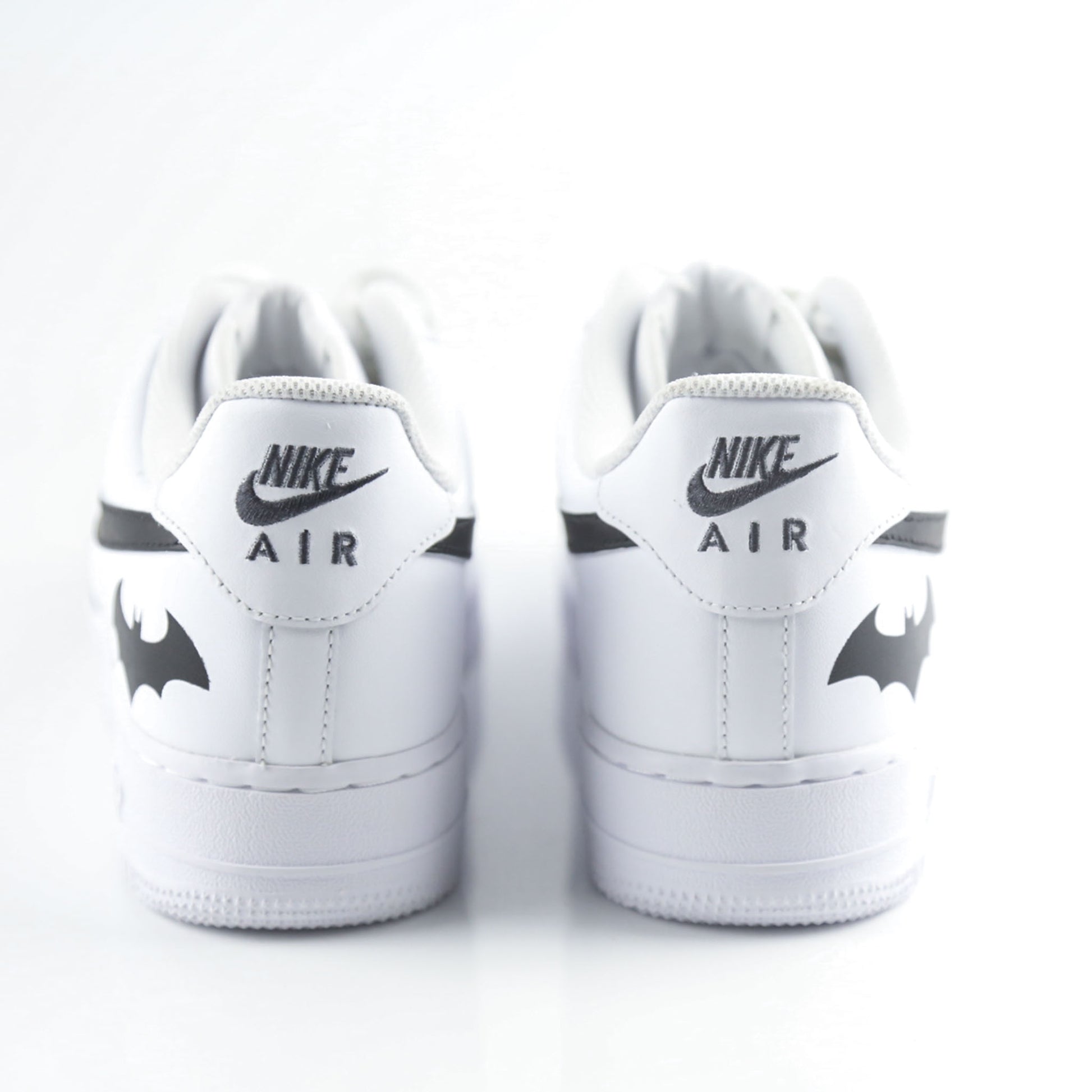 Nike Air Force 1 Custom blanche avec swoosh noir et logo Batman à l’arrière, inspirée de Gotham City, Batman, le Joker et l’univers DC Comics. Sneakers customisées streetwear haut de gamme pour fans de super-héros, comics et baskets personnalisées.
