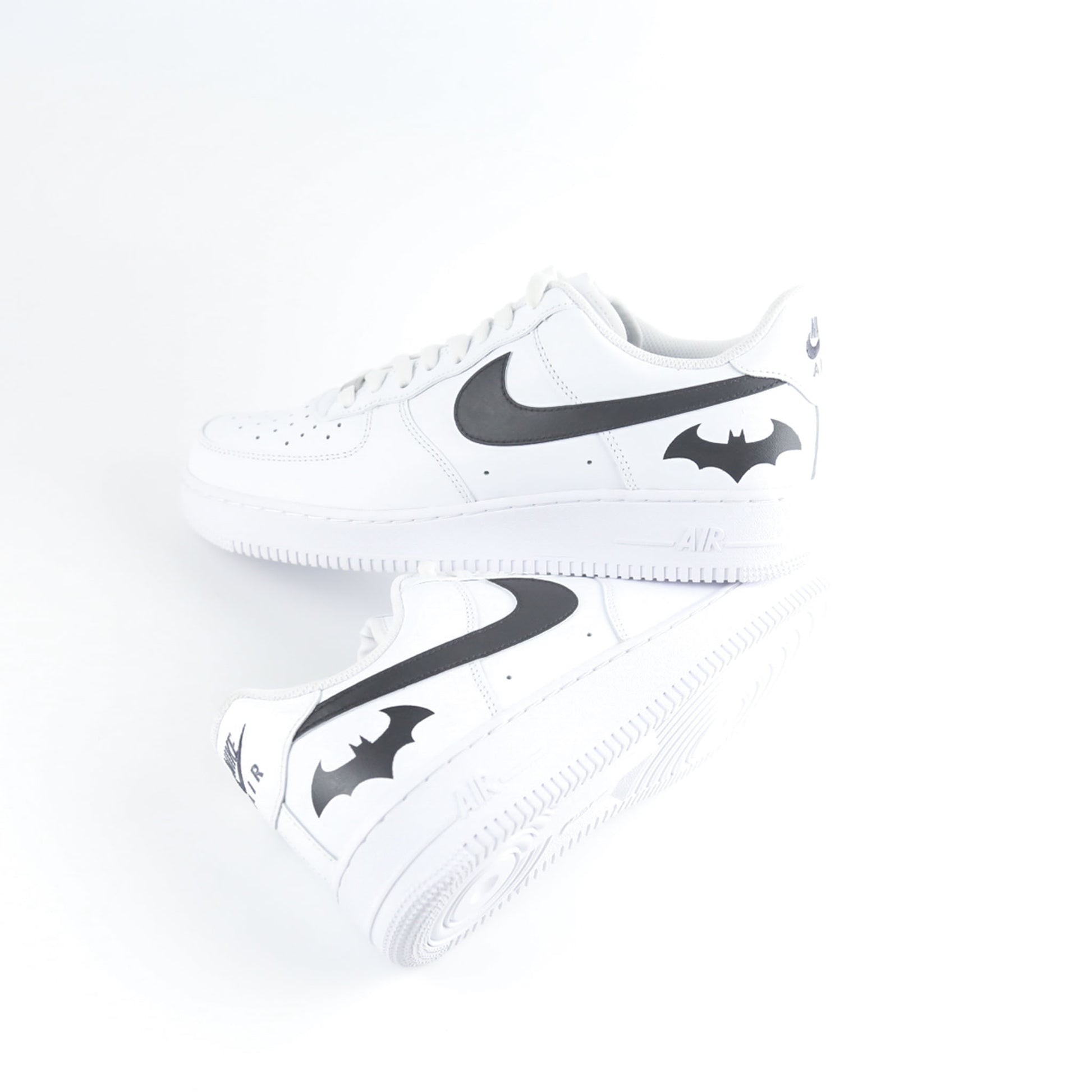 Nike Air Force 1 Custom blanche avec swoosh noir et logo Batman à l’arrière, inspirée de Gotham City, Batman, le Joker et l’univers DC Comics. Sneakers customisées streetwear haut de gamme pour fans de super-héros, comics et baskets personnalisées.