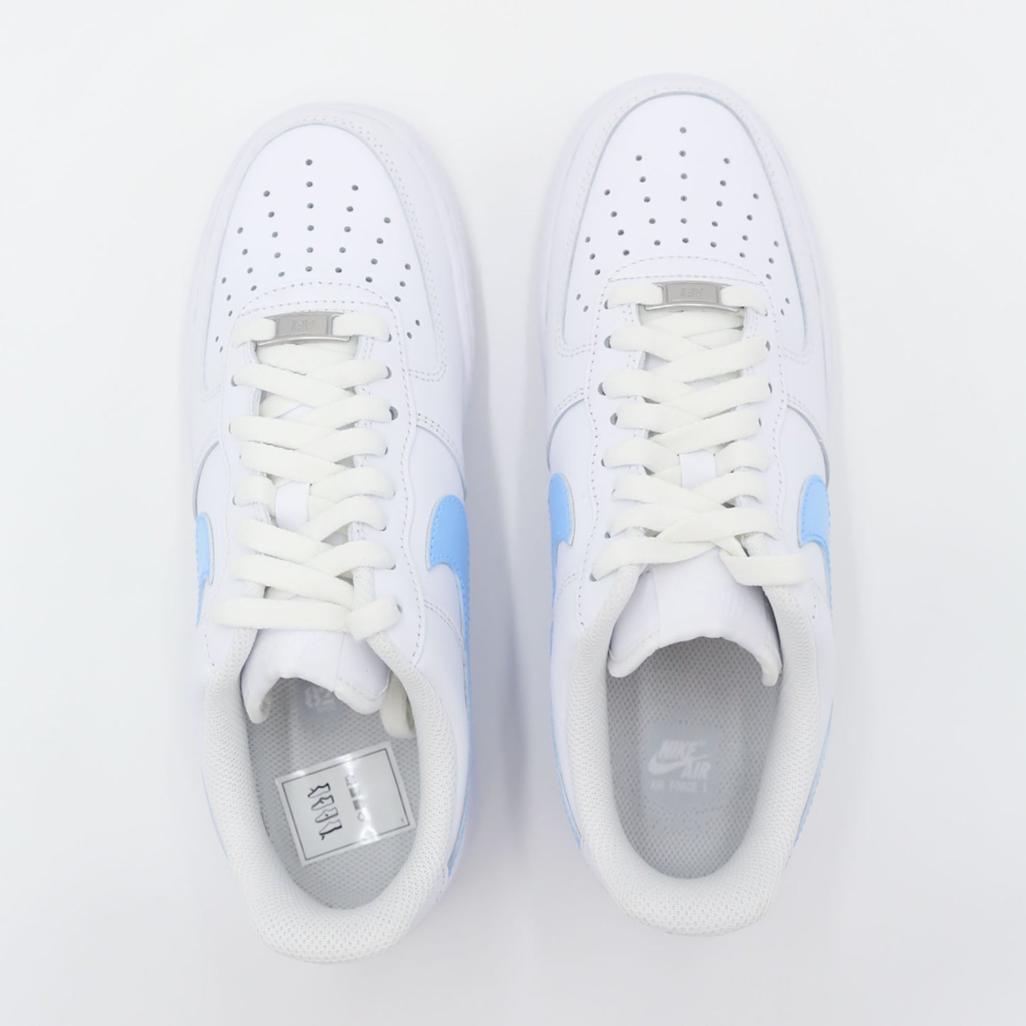 Nike Air Force 1 Custom blanche avec swoosh bleu ciel, design moderne et épuré pour un style unique. Sneakers customisées offrant confort, durabilité et polyvalence, idéales pour les tenues streetwear et casual.