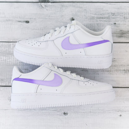 Nike Air Force 1 custom avec swoosh violet pastel sur fond bois clair